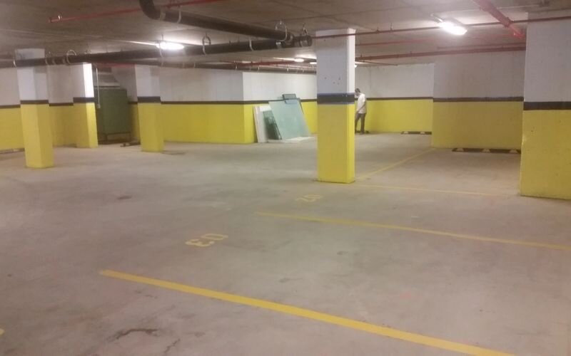 A parking garage with yellow walls and white pillars.