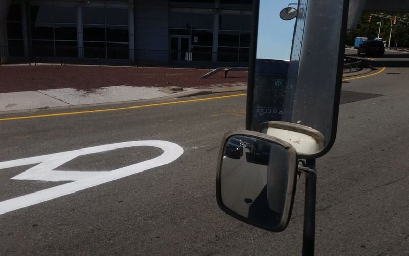 A mirror on the side of a road with a street sign in the background.