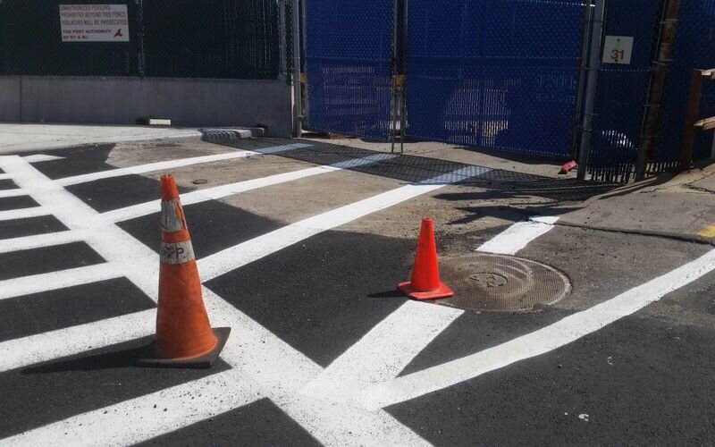 A street with orange cones and white lines.