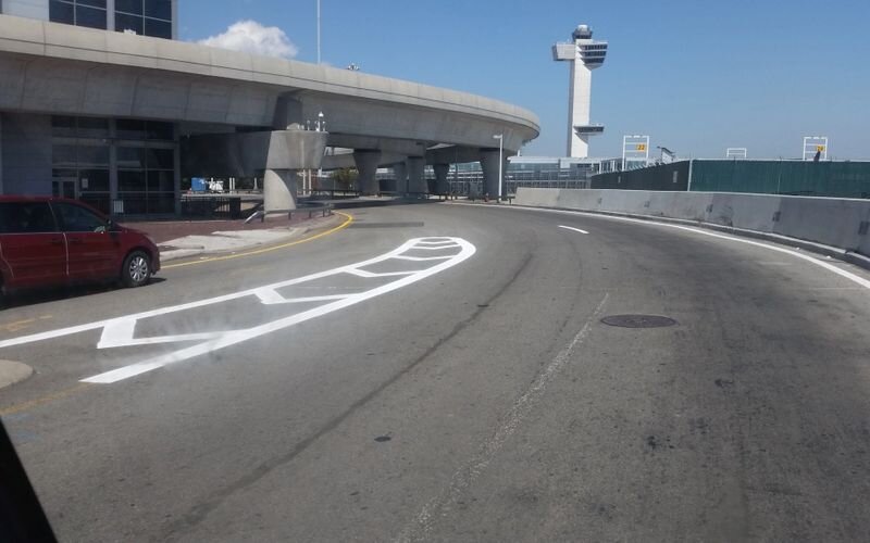 A road with markings on it and an airport in the background.