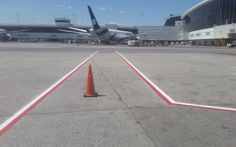 A runway with an orange cone in the foreground and an airplane on the ground.