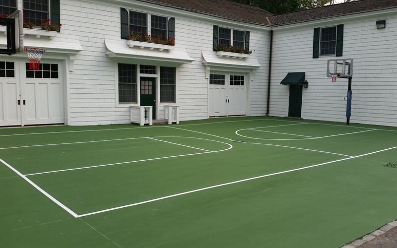 A tennis court in front of two white houses.