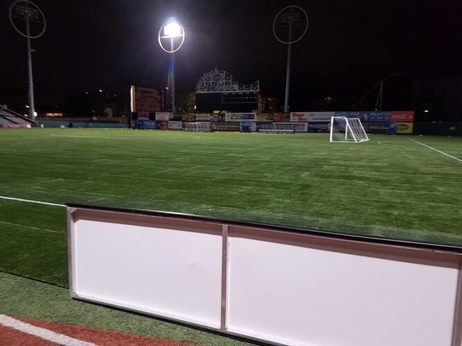 A baseball field with the lights on at night.