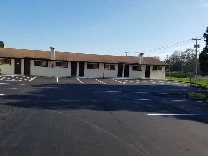 A parking lot with several motel rooms in the background.