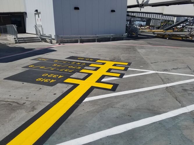 A parking lot with yellow lines and white markings.