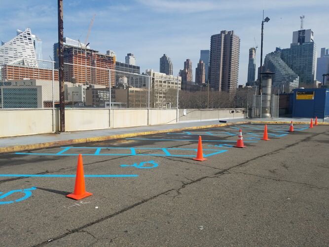 A street with orange cones and blue lines on the ground.