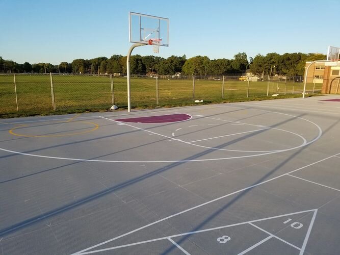 A basketball court with a net and trees in the background.