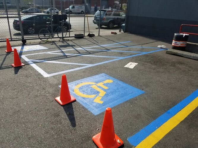 A parking lot with orange cones and handicapped sign painted on it.