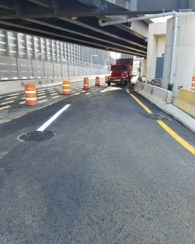 A truck is driving down the street under a bridge.