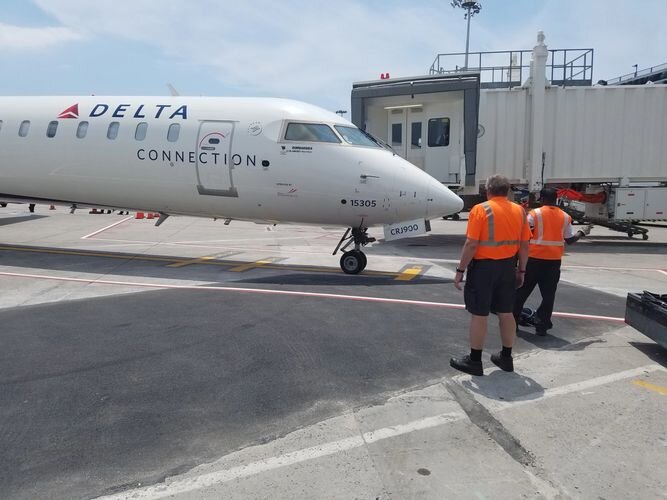 A delta connection airplane on the tarmac with workers.