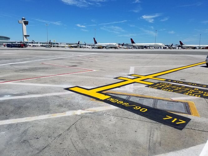 A yellow and black airport runway with airplanes on the tarmac.