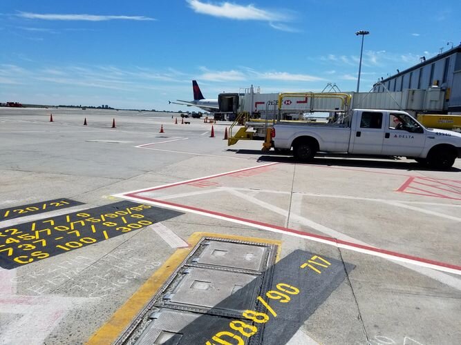 A white truck parked on the side of an airport runway.